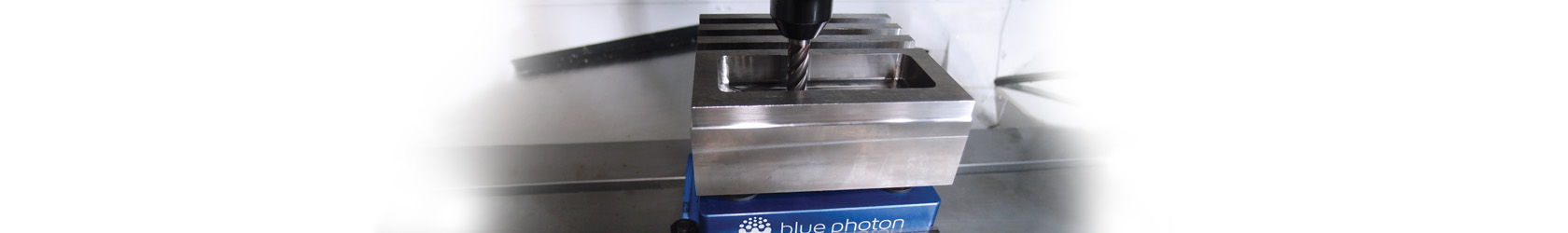 Photo of a drill press drilling a hole into a metal part, held in place by Blue Photon light-activated adhesive
