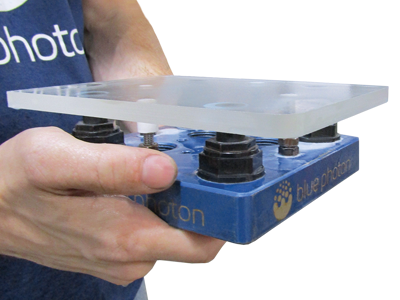 Photo of the Blue Photon Workholding system securely holding a thick piece of glass, ideal for optical applications by reducing scrap and the chance of the part breaking.